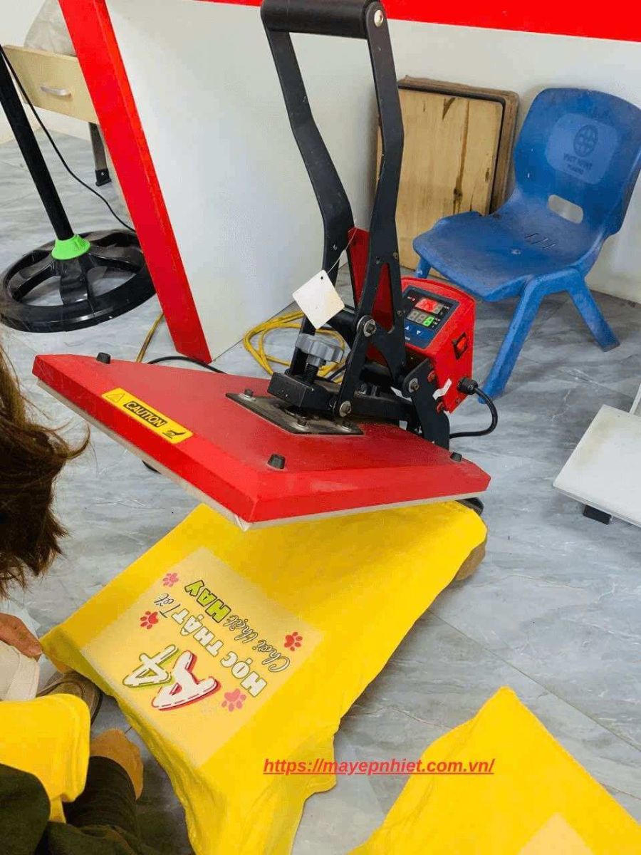 Máy ép nhiệt 32x45 đang ép decal chuyển nhiệt lên áo thun đồng phục